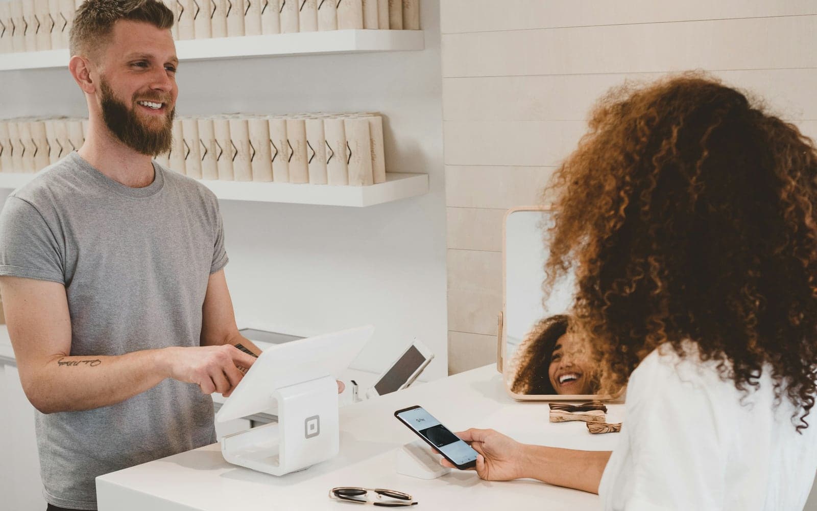 A returning customer paying at a counter, greeted by the owner
