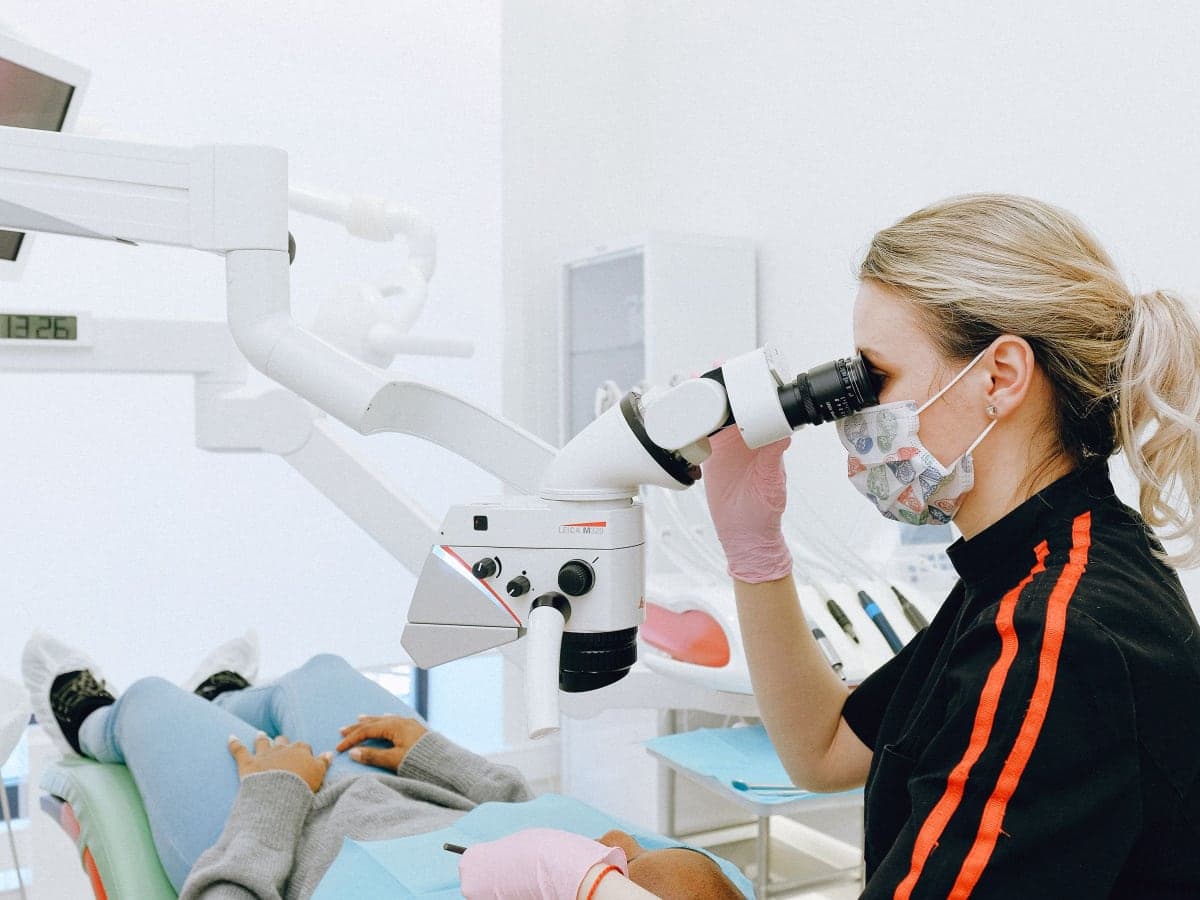 A dentist examining a patient through a dental microscope