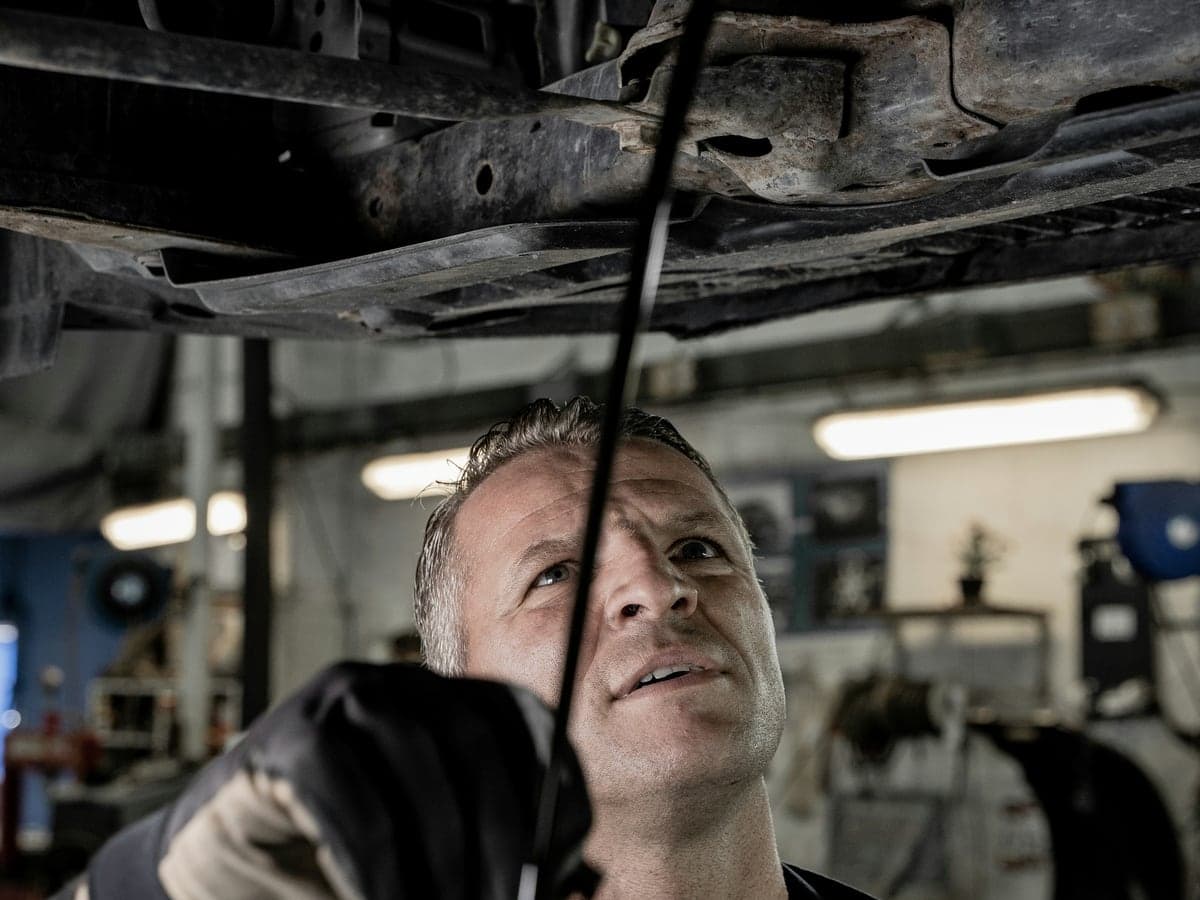A mechanic working underneath a car in a garage