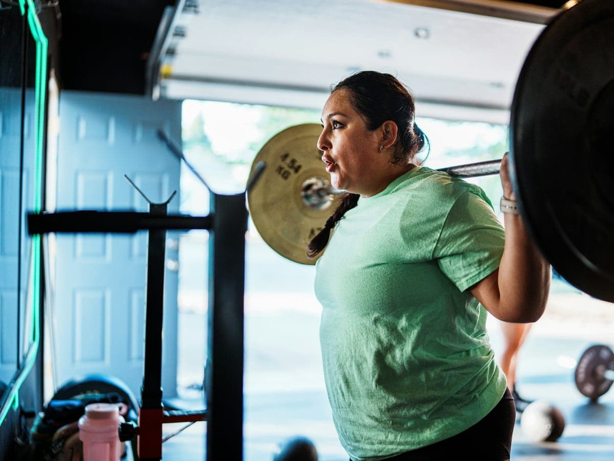 A woman lifting a barbell in a gym
