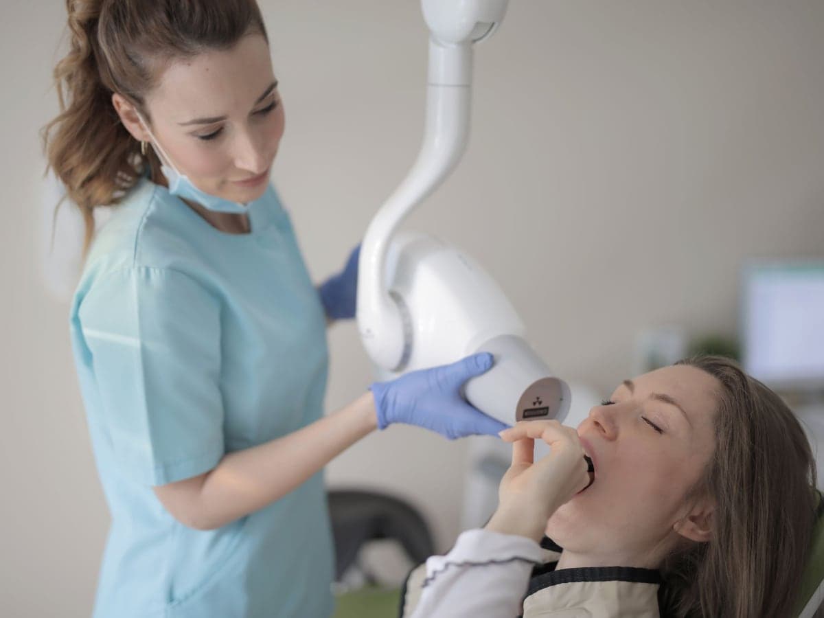 A clinician positioning an imaging arm beside a patient in a treatment chair
