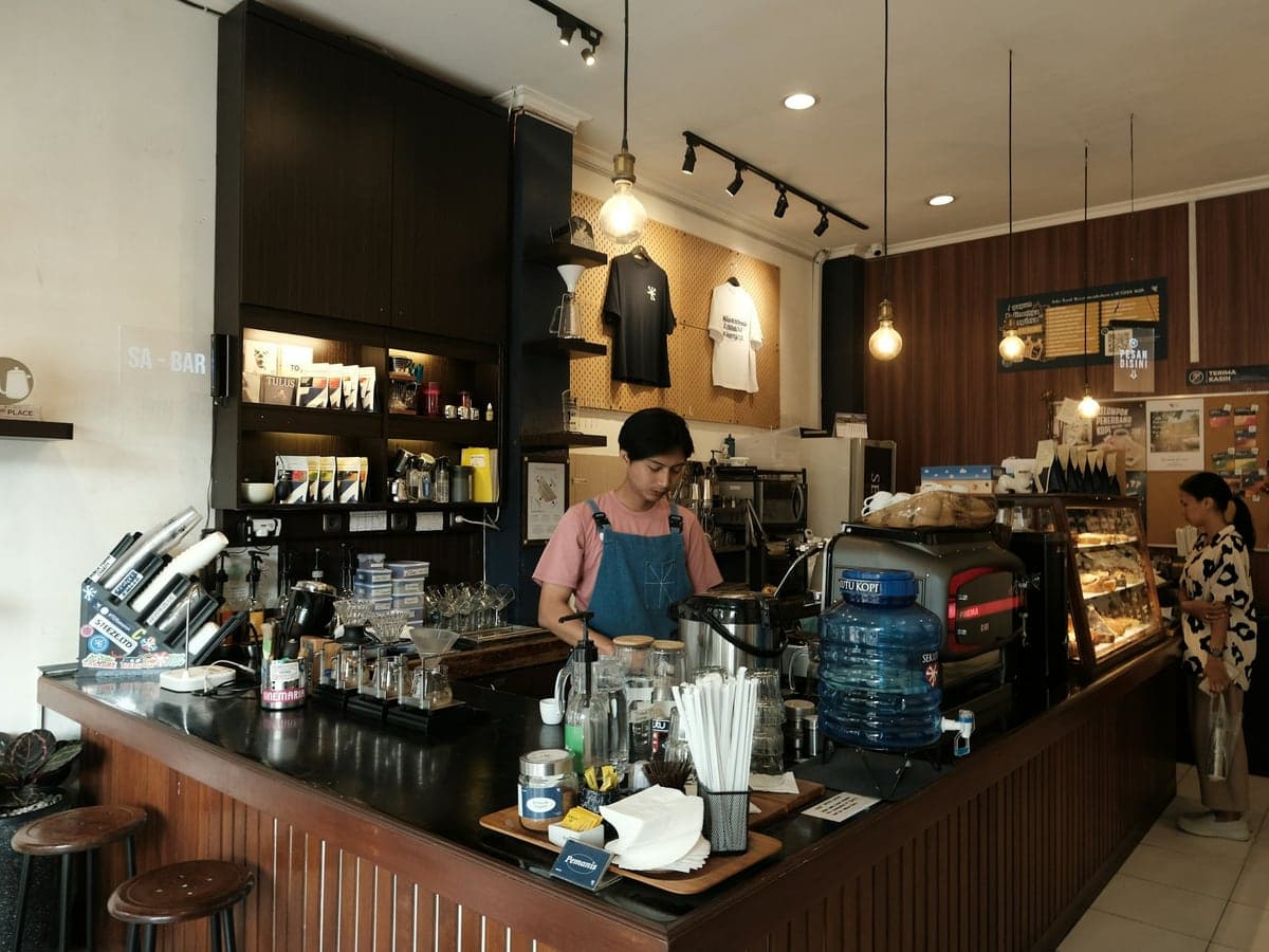 A café counter with a barista at work behind it