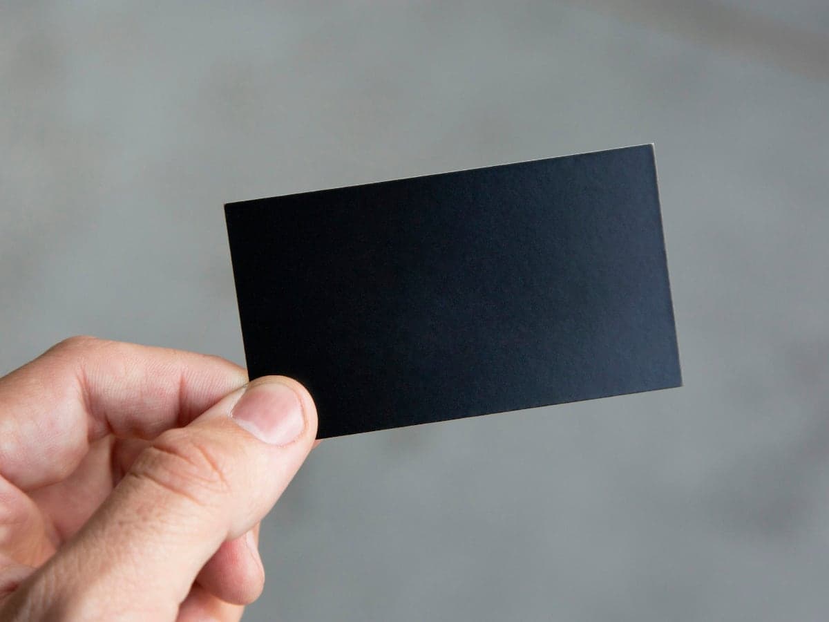 A hand holding up a blank black card