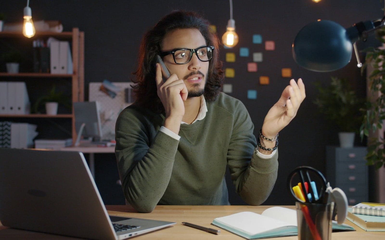 A business owner on a phone call at his desk, laptop and notes in front of him