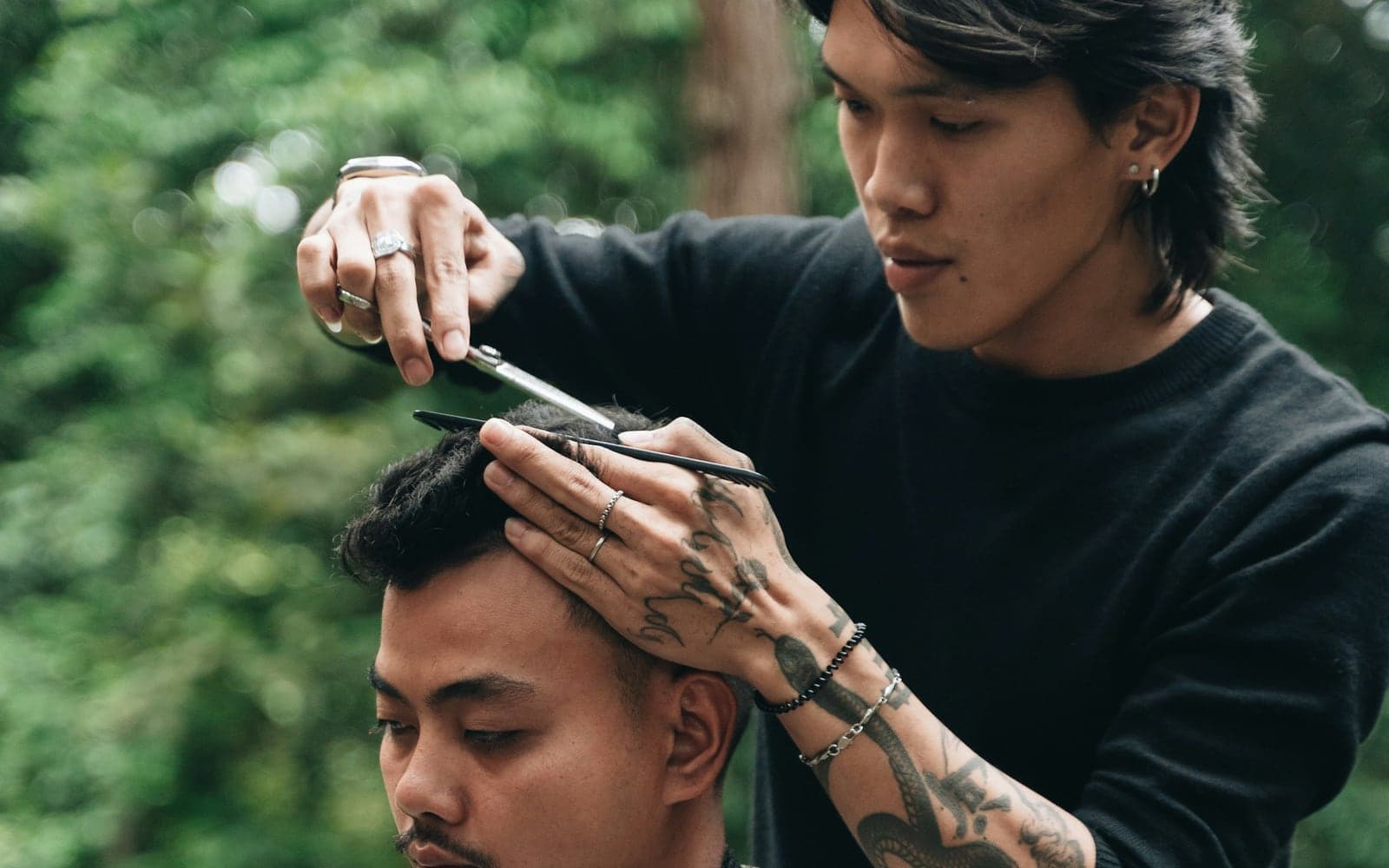 A barber at work, cutting a client's hair outdoors